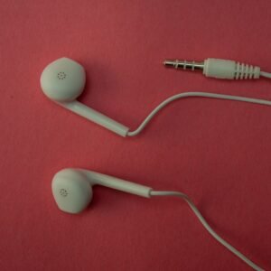 White earbuds and their cable on a pink surface.